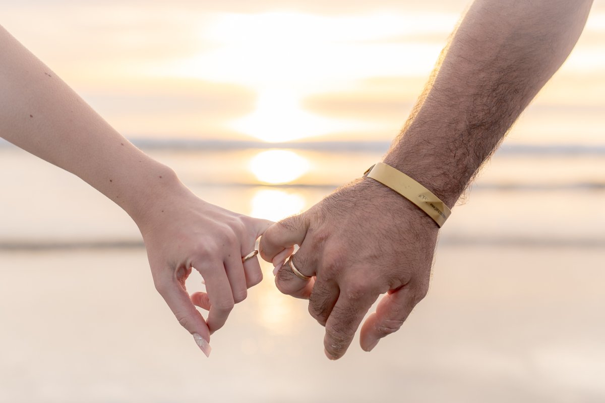 Romantic detail – wedding rings photo by the sea at sunrise in Playa del inglés Close-up of a couple's hands with wedding rings during sunrise at the beach in Playa del inglés